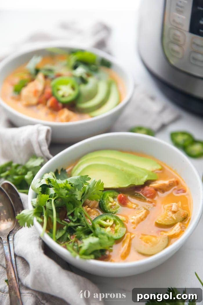 Two bowls of Whole30 Instant Pot chicken tortilla-less soup, generously garnished with sliced avocado, fresh cilantro, and jalapeños for a vibrant presentation.