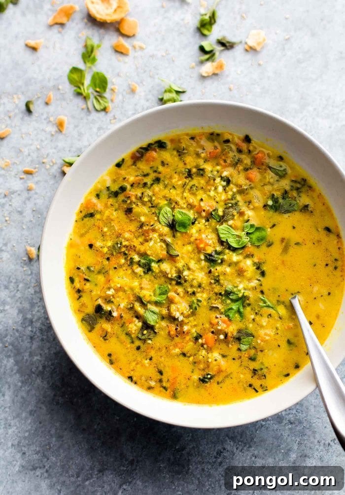A white bowl brimming with fragrant Curried Cauliflower Rice Kale Soup, showing its vibrant colors and textures.