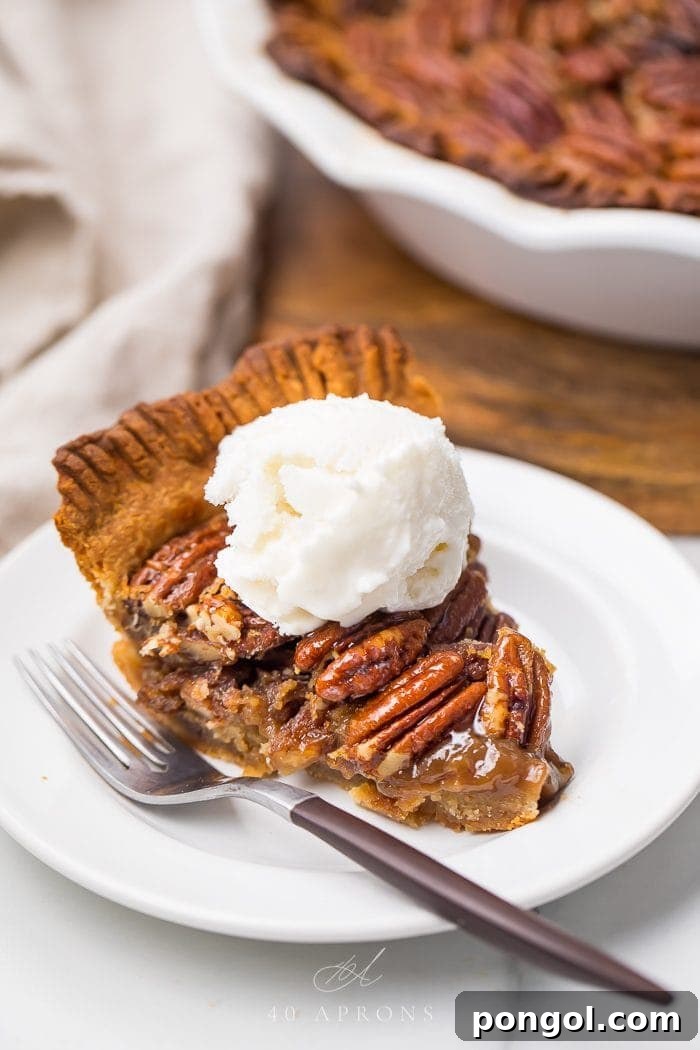 A beautifully sliced paleo pecan pie, served on a plate with a dollop of dairy-free whipped cream, ready to be enjoyed.