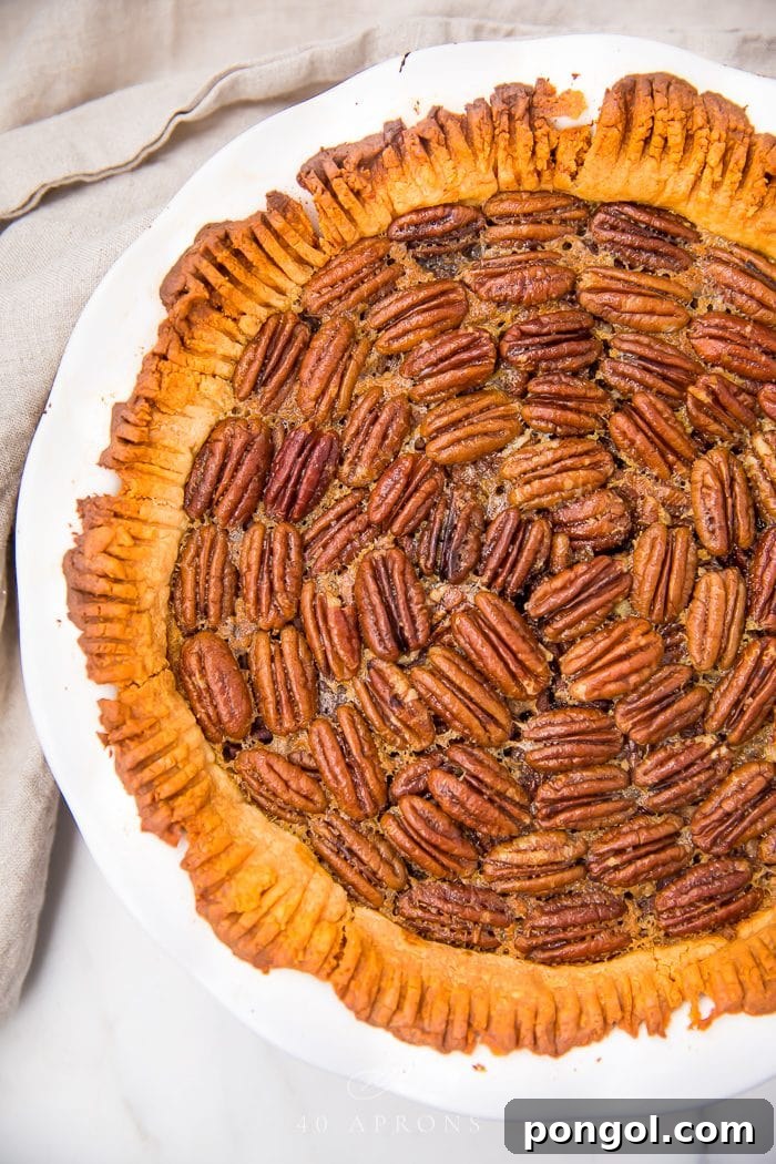 A freshly baked paleo pecan pie, golden brown and glistening with a perfect pattern of pecans on top, cooling on a wire rack.