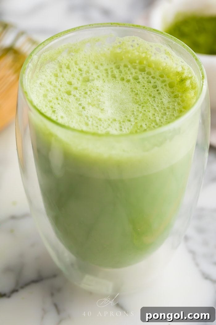A beautifully prepared matcha latte is served in a clear glass mug, showcasing its vibrant green color and frothy texture, a healthy and energizing beverage choice.