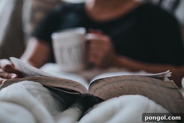 A serene image of a man comfortably reading a physical book in bed, holding a warm mug of tea, illustrating a peaceful pre-sleep routine for winding down.