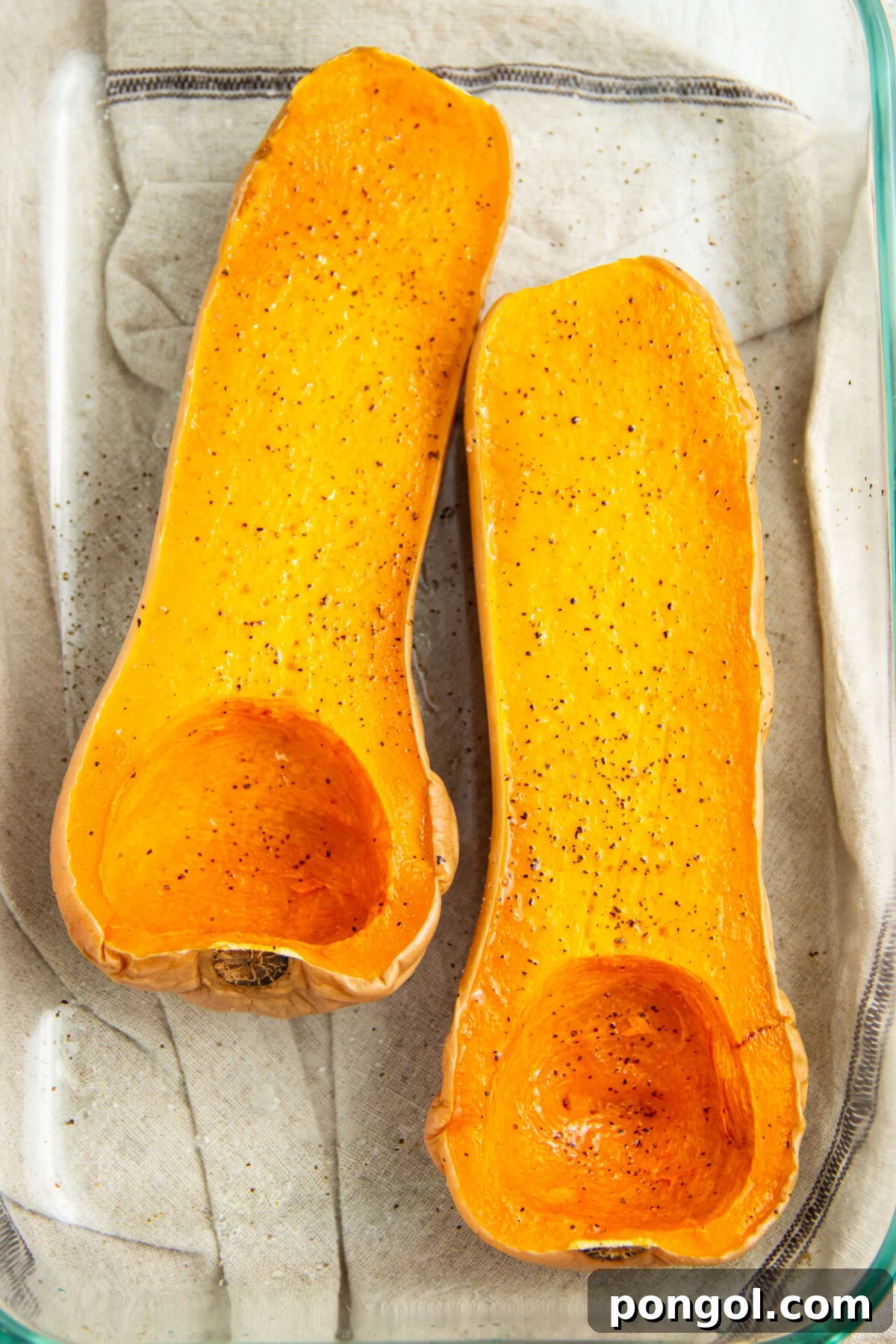 Halved butternut squash in a microwave-safe baking dish.