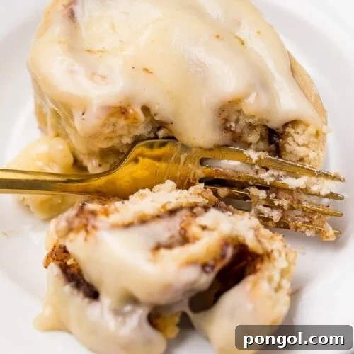 A beautiful gluten-free cinnamon roll cut in half, showcasing its rich cinnamon swirl and gooey texture, ready for serving.