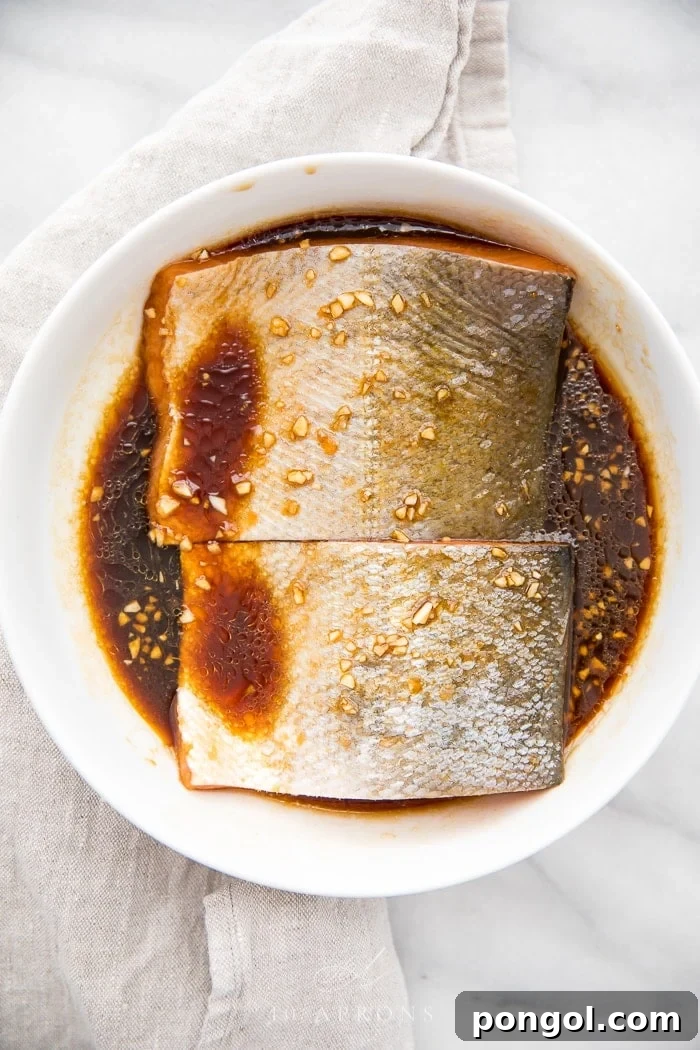 Salmon fillets marinating in a homemade teriyaki sauce, showcasing the rich color of the marinade