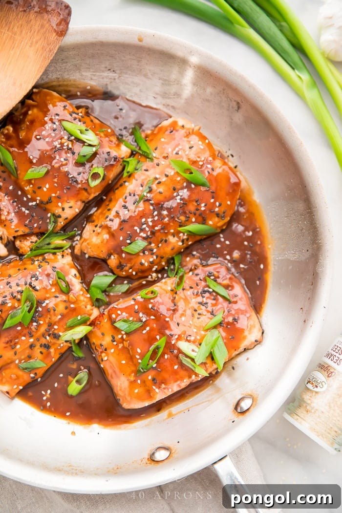 Perfectly cooked salmon fillets in a white bowl, generously coated with glistening teriyaki sauce