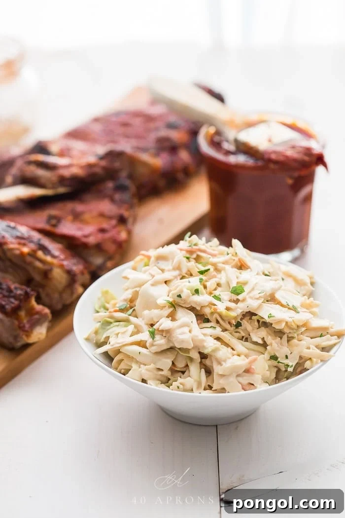 Healthy coleslaw in a white bowl infront of some ribs