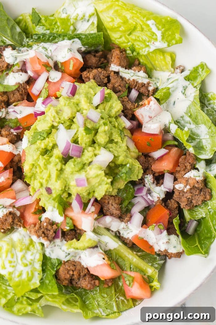 A beautifully presented healthy taco salad in a pristine white bowl, showcasing its vibrant layers.