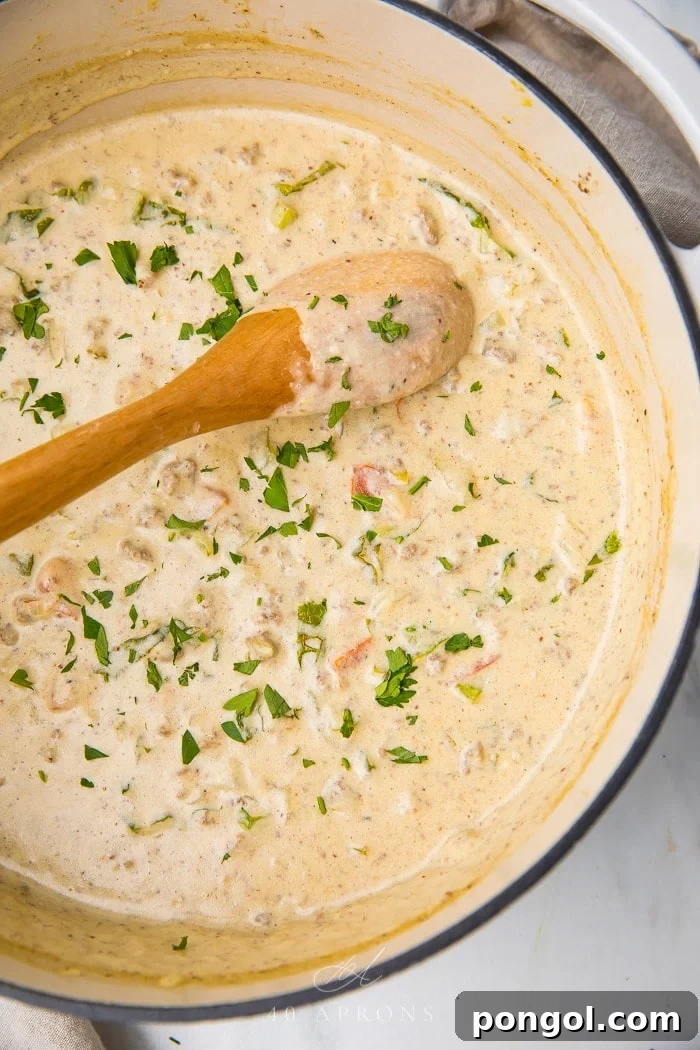 Stirring the cheeseburger soup in a pot with a wooden spoon, showcasing its rich texture