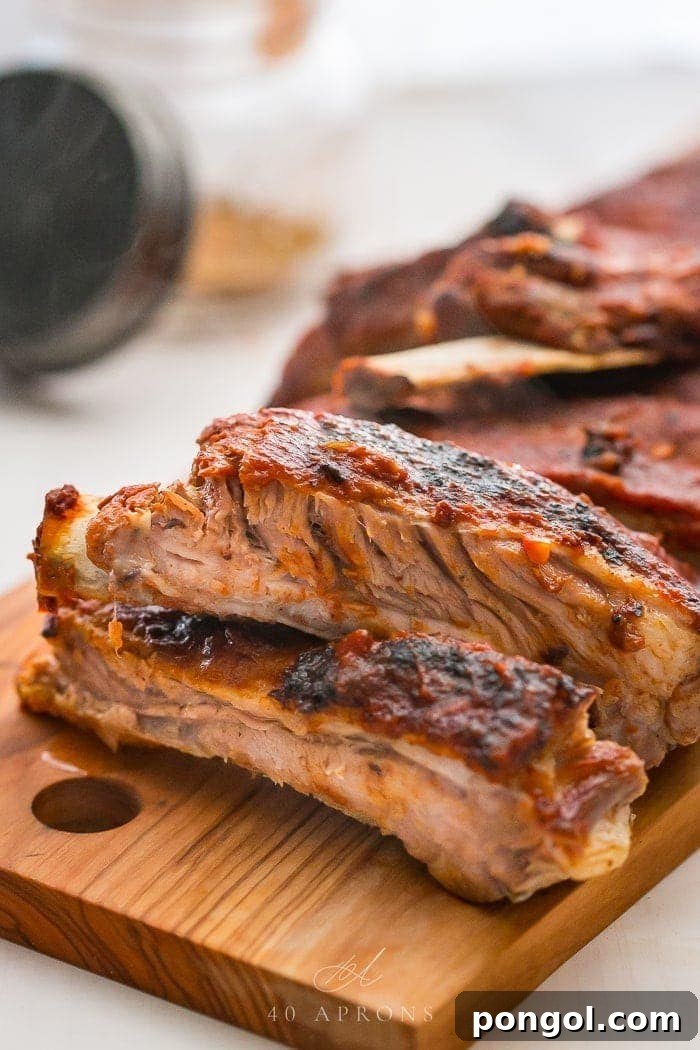 Close up of perfectly cooked Instant Pot baby back ribs on a chopping board, glistening with BBQ sauce