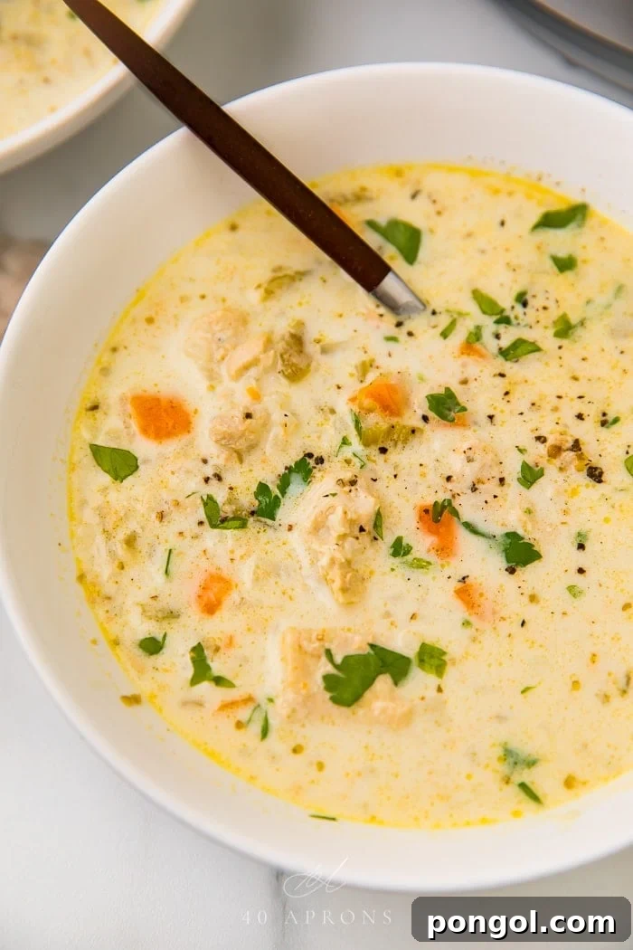 A serving of chicken and cauliflower rice soup in a bowl, garnished with fresh herbs, ready to be eaten.