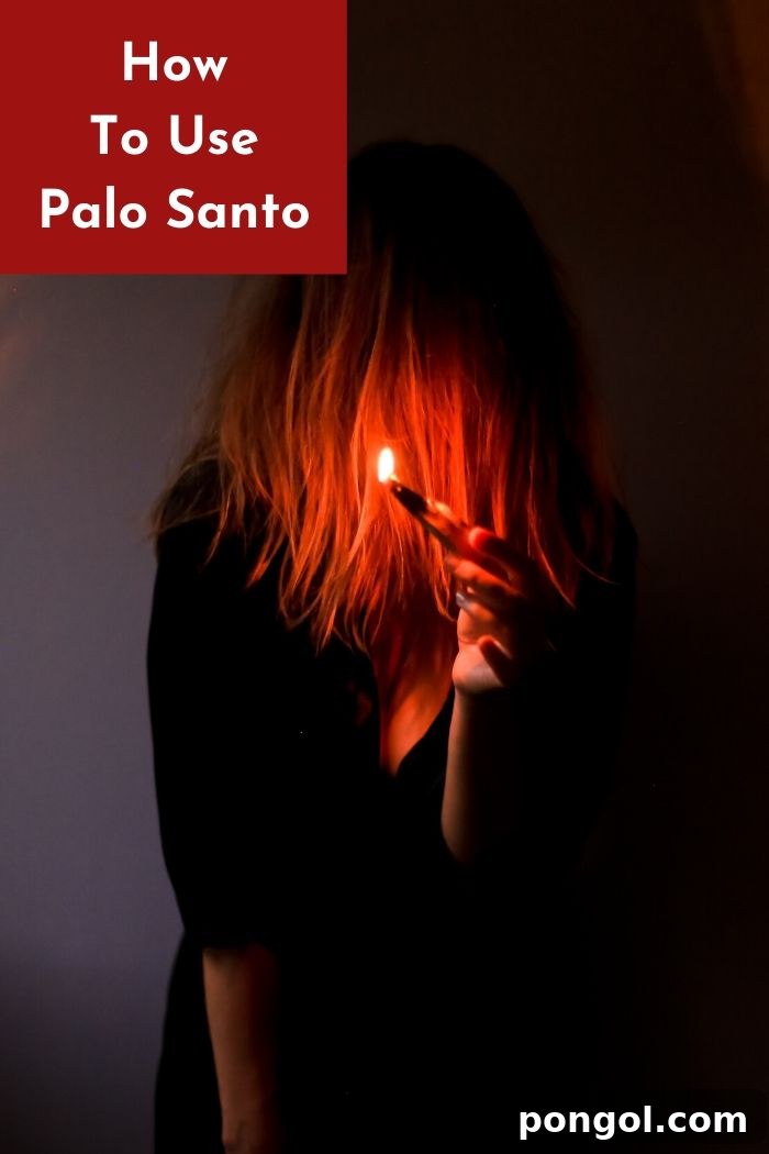 A woman holding a lit Palo Santo wood stick, smoke rising gently