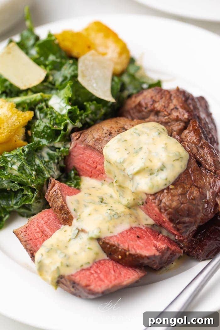 medium rare filet mignon with bearnaise sauce on white plate with kale Caesar salad