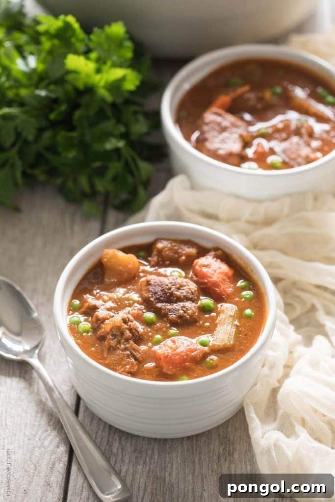 Two white bowls generously filled with rich Whole30 Beef Stew, featuring tender beef, hearty vegetables, and a luscious, savory broth, ready to be enjoyed.