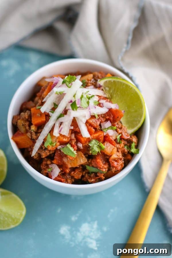 A white bowl holds a generous portion of Slow Cooker Sweet Potato Chili, showcasing its rich, warm colors and enticing texture, ready for a flavorful, healthy meal.