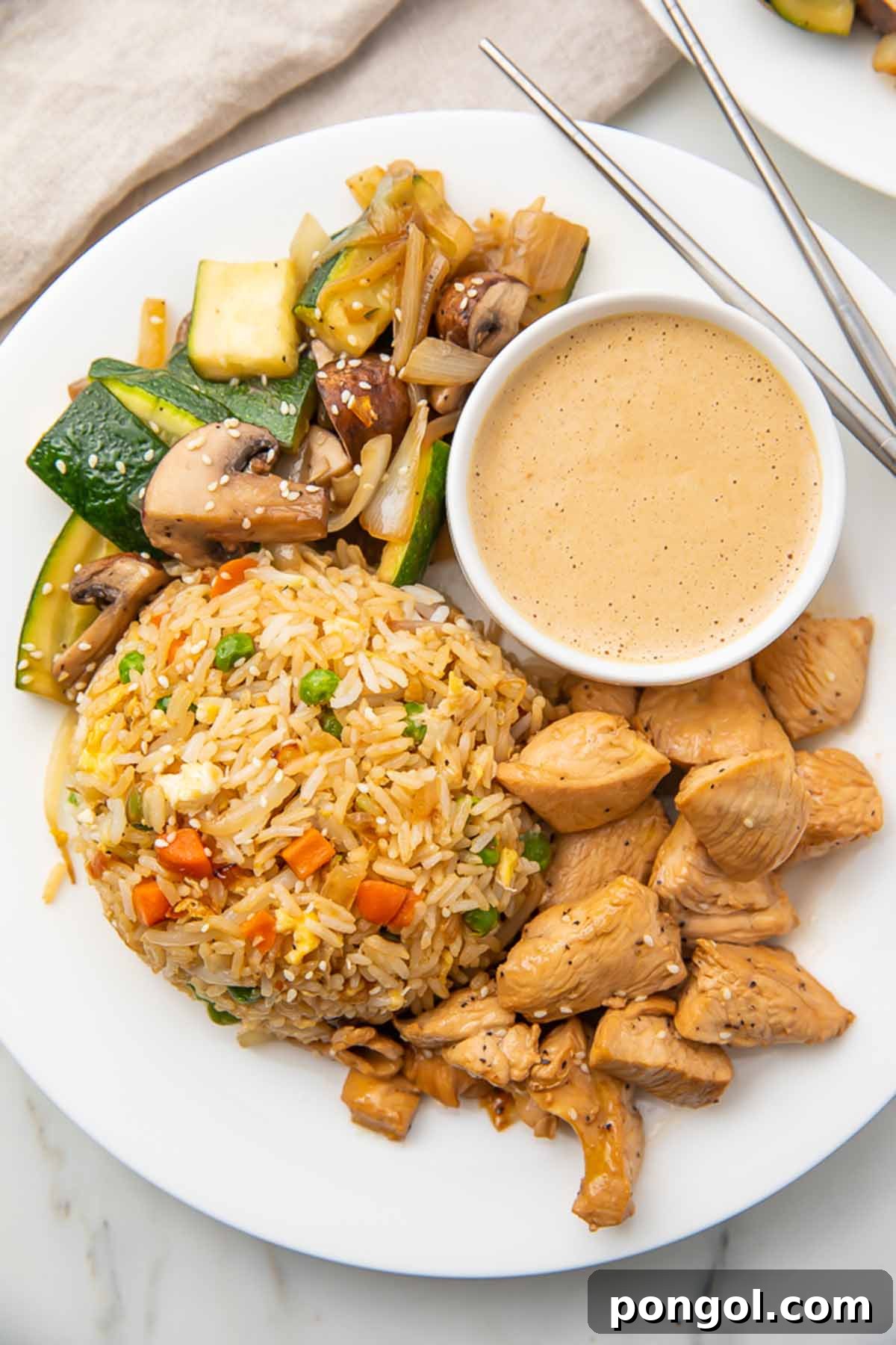 Sizzling Hibachi Chicken Dinner 4 A perfectly plated hibachi chicken and fried rice meal, complete with colorful vegetables and a side of creamy mustard dipping sauce.