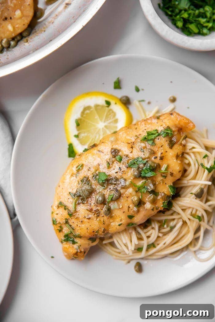 Paleo Gluten Free Lemon Chicken Piccata 2 Chicken piccata served over pasta on a white plate