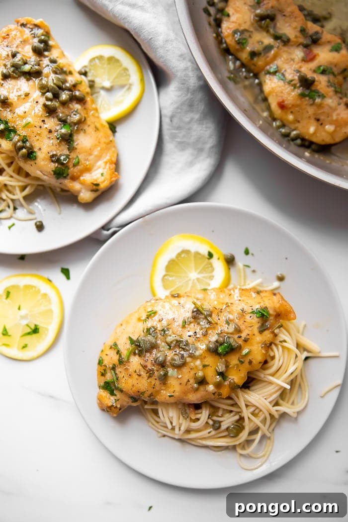 Paleo Gluten Free Lemon Chicken Piccata 4 Two plates of chicken piccata served over pasta with lemon.