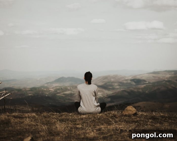 Woman sitting outside looking at mountains, embracing nature and tranquility