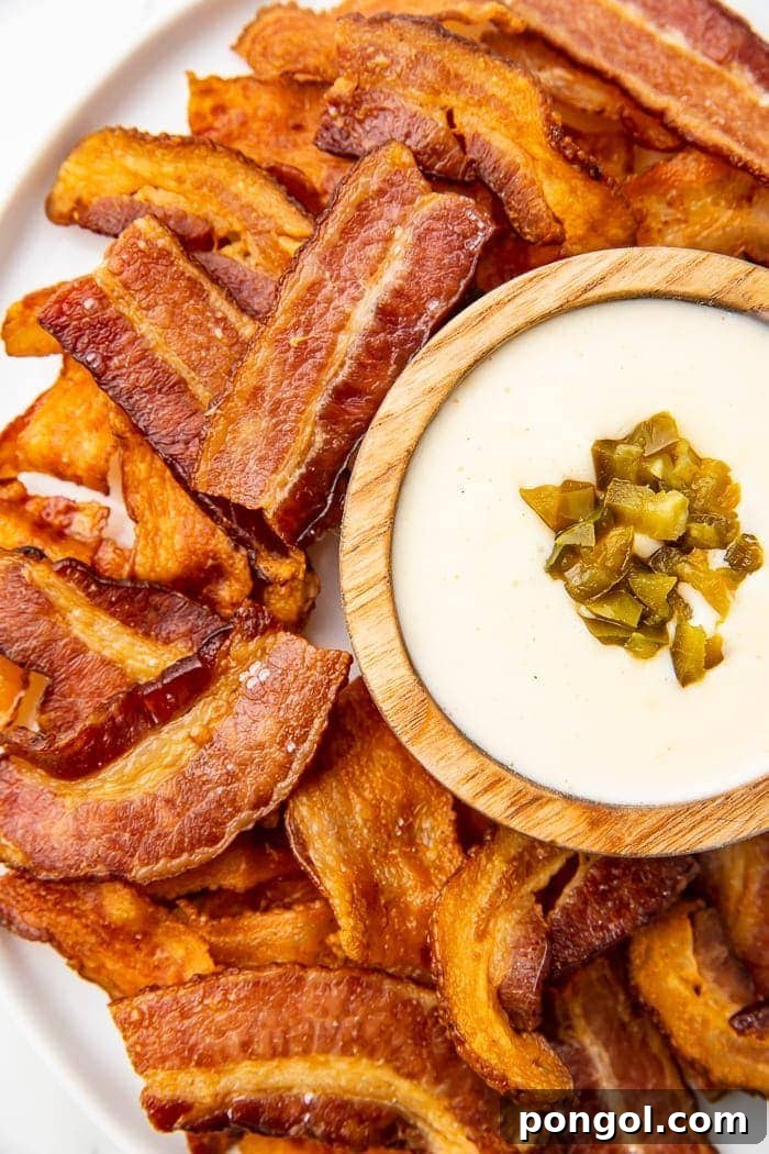 Keto Bacon Crunch 2 Crispy Keto Bacon Chips displayed with a vibrant green guacamole dip, ideal for low-carb snacking.