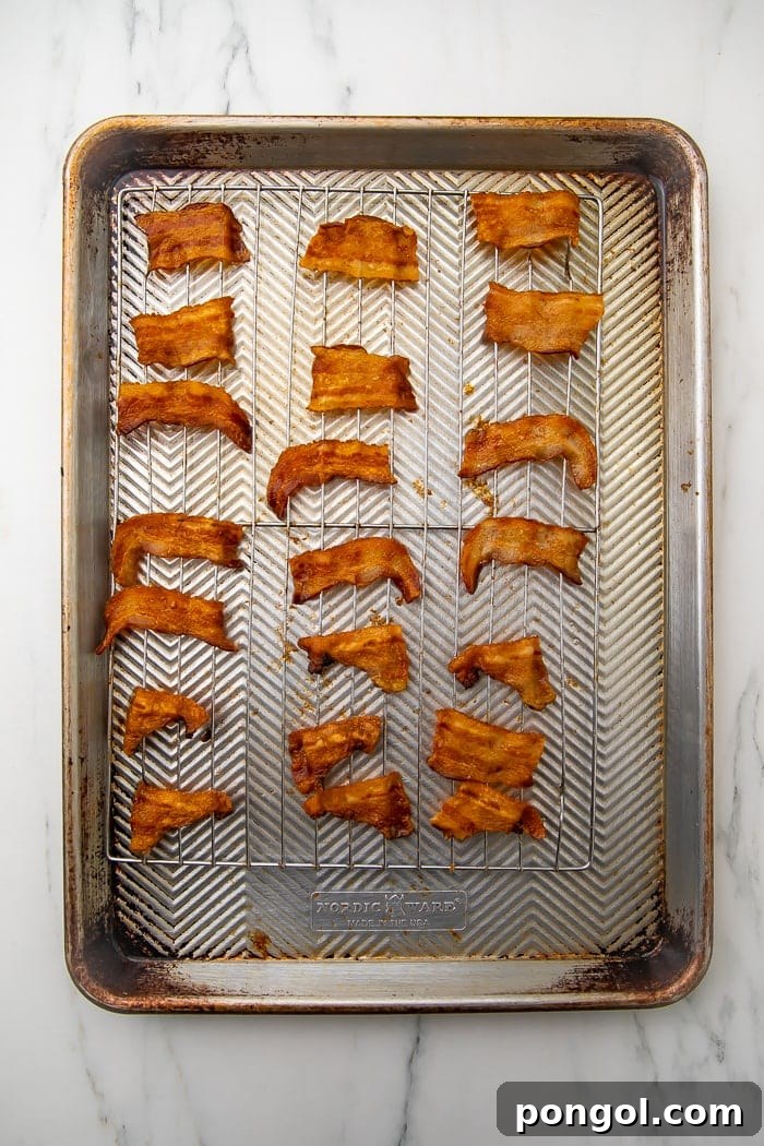 Keto Bacon Crunch 4 Two hands reaching for golden, crispy bacon chips from a bowl, highlighting their snack appeal.