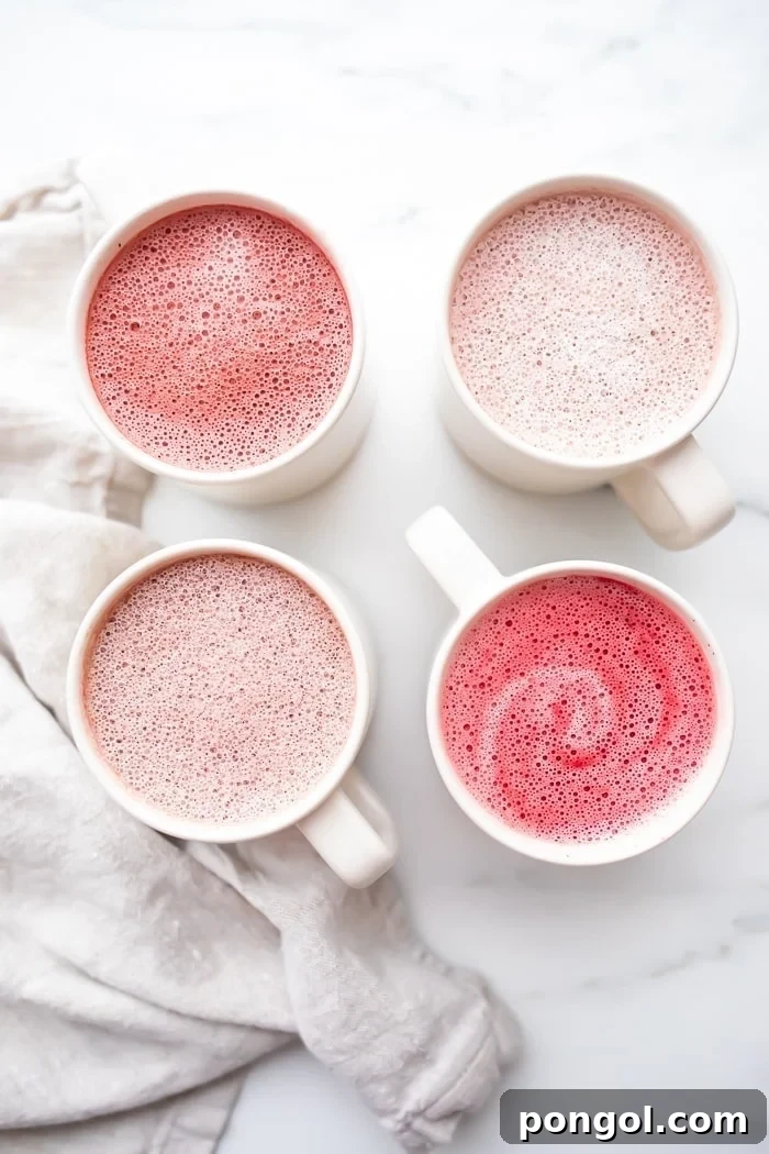 Four pink lattes in white mugs