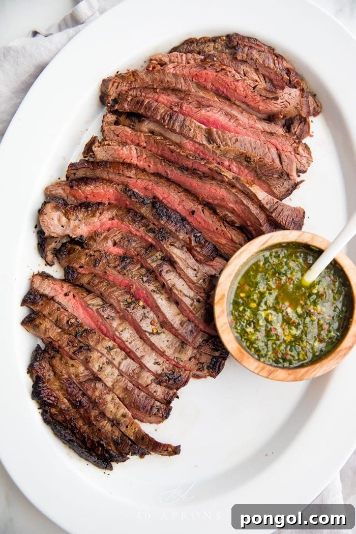 Flavorful Whole30 Dinner Ideas 24 A flank steak sliced against the grain into strips, with a small bowl of fresh chimichurri sauce on the side.