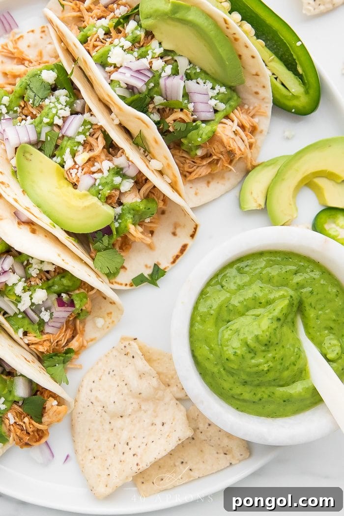 Flavorful Whole30 Dinner Ideas 12 Crockpot chicken tacos served with a separate bowl of creamy avocado cilantro sauce.