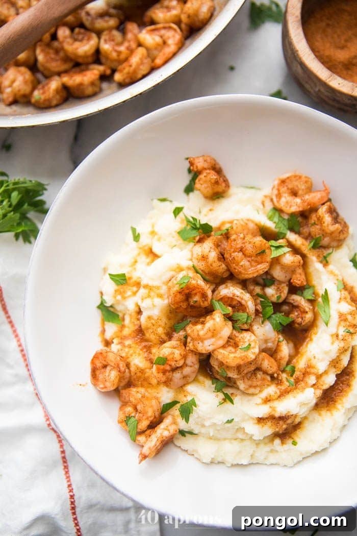 Flavorful Whole30 Dinner Ideas 37 Whole30 healthy shrimp and grits in a bowl, with a skillet blurred in the background.