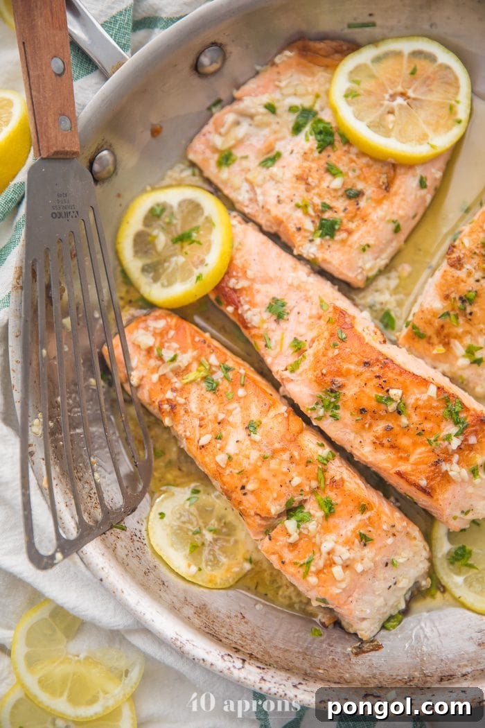 Flavorful Whole30 Dinner Ideas 38 Lemon garlic salmon in a skillet with lemon slices and a fish turner.