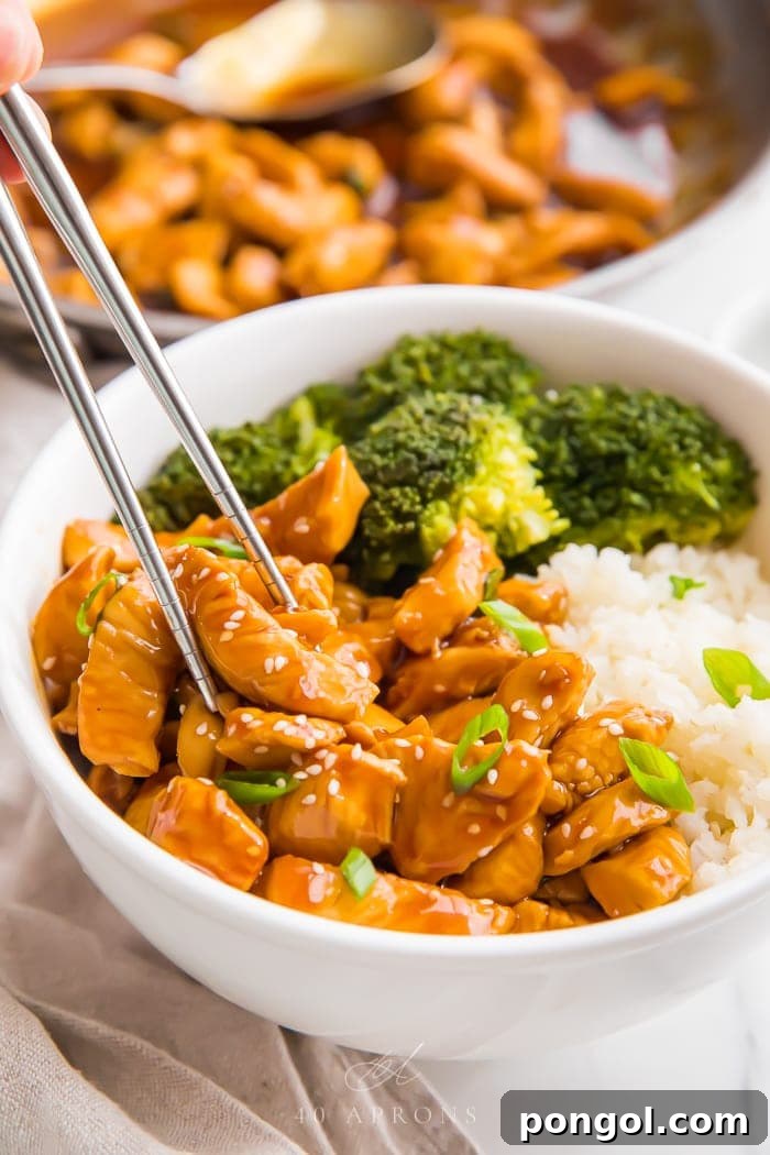 Flavorful Whole30 Dinner Ideas 20 Chopsticks picking up a piece of Whole30 teriyaki chicken from a bowl.