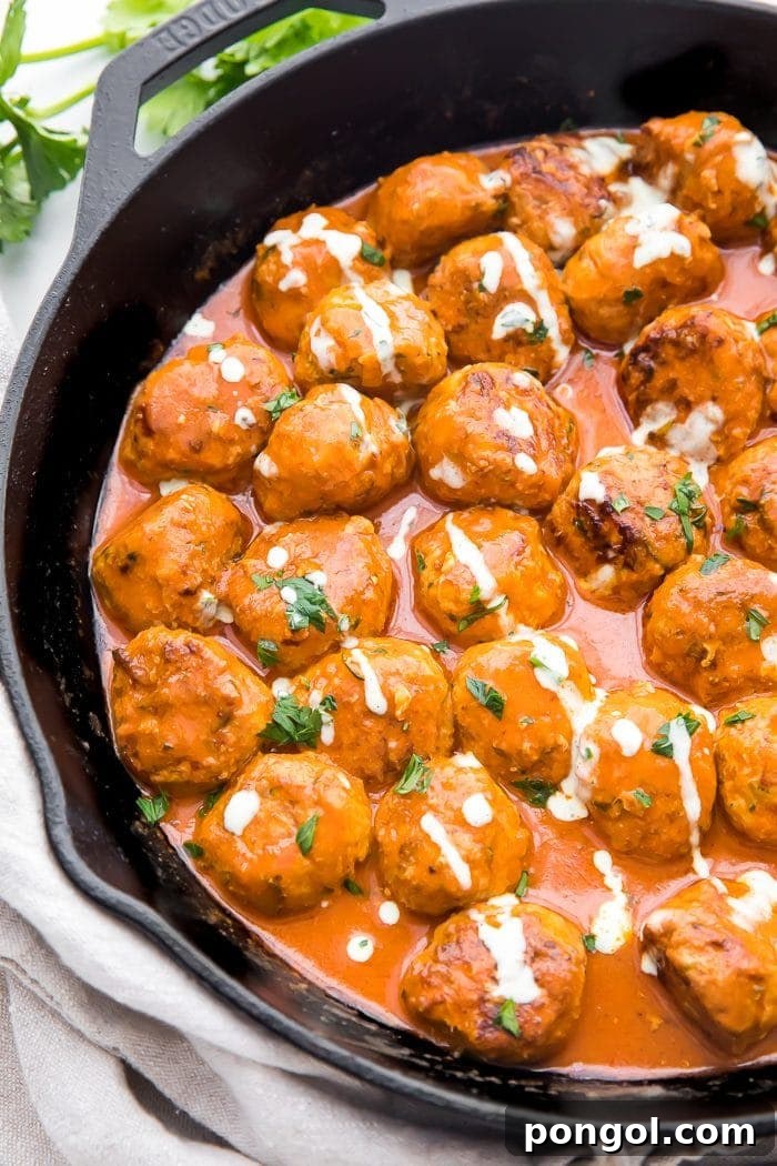 Flavorful Whole30 Dinner Ideas 8 Buffalo chicken meatballs served in a dish, coated in creamy sauce and drizzled with ranch dressing.