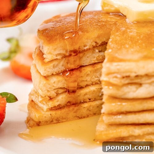 Syrup poured over a stack of gluten-free pancakes after a wedge has been cut out, revealing the fluffy interior.