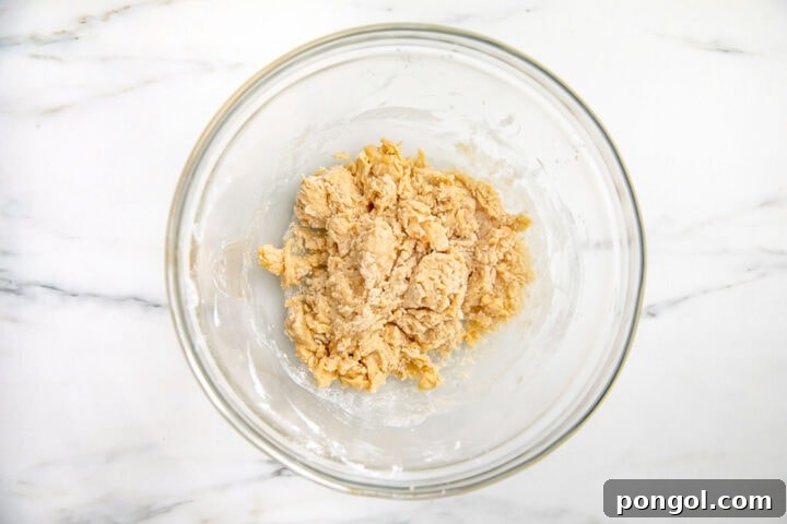 Dry ingredients added to wet ingredients in large glass mixing bowl, showing the next step in batter preparation.