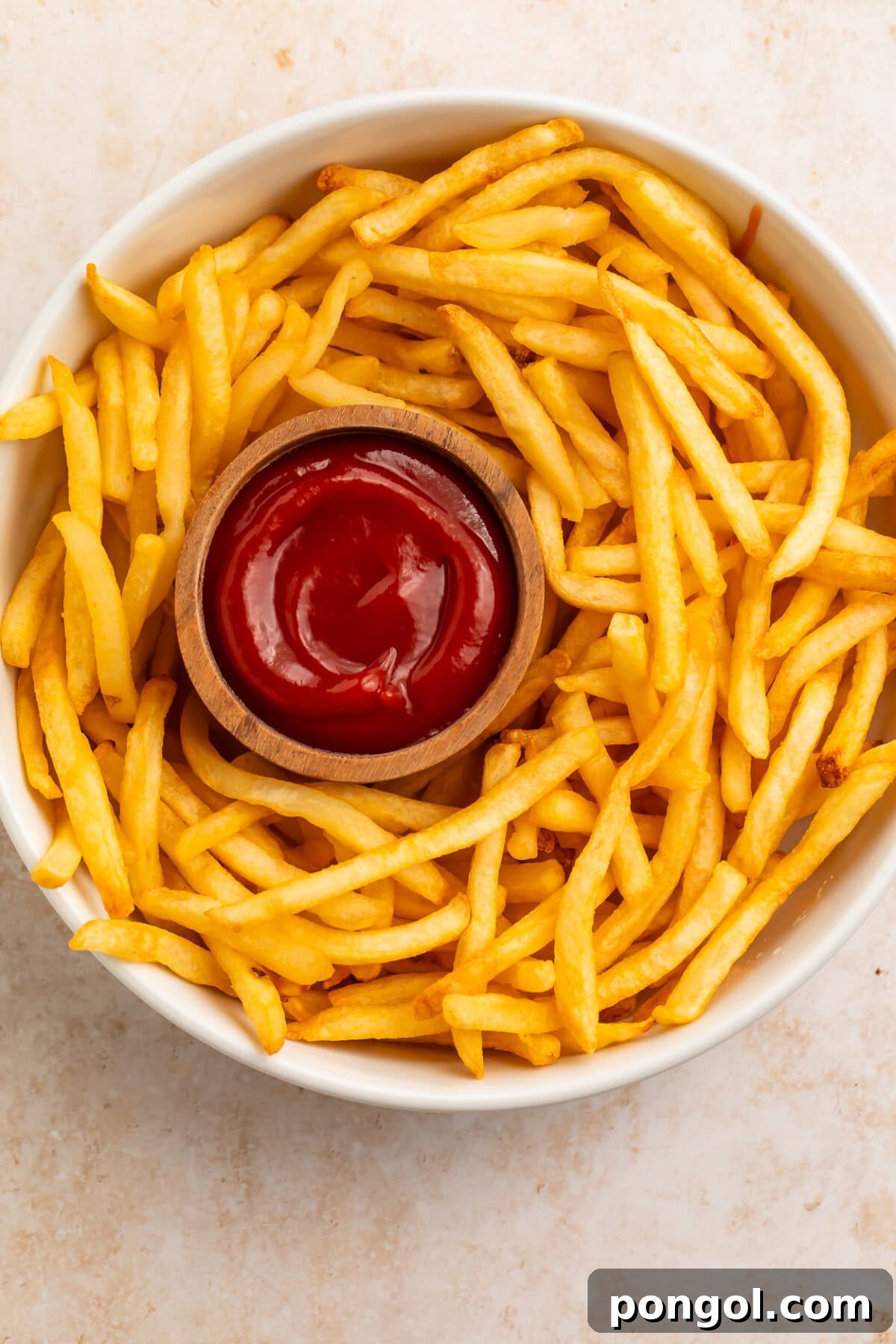Crispy air fryer french fries arranged on a white plate with ketchup dipping sauce.