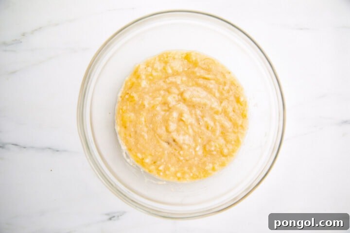 3 mashed bananas in a large glass mixing bowl.