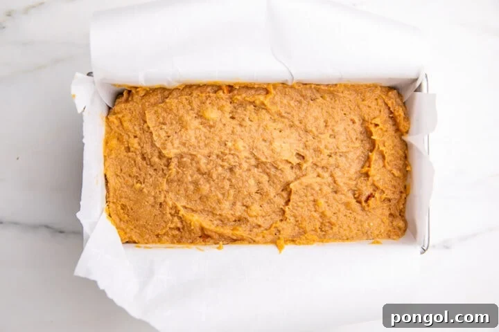 Prepared paleo almond flour banana bread batter in loaf pan lined with parchment paper.