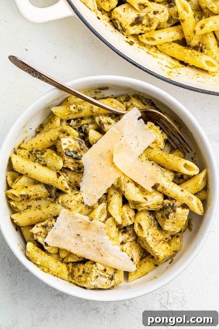 One-pot chicken pesto pasta in a bowl topped with Parmesan cheese