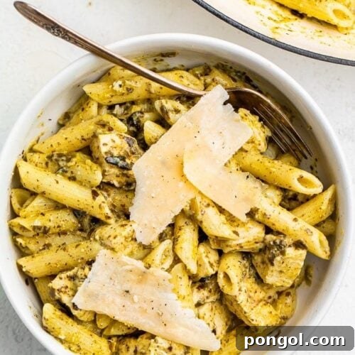 One-pot chicken pesto pasta in a bowl topped with Parmesan cheese