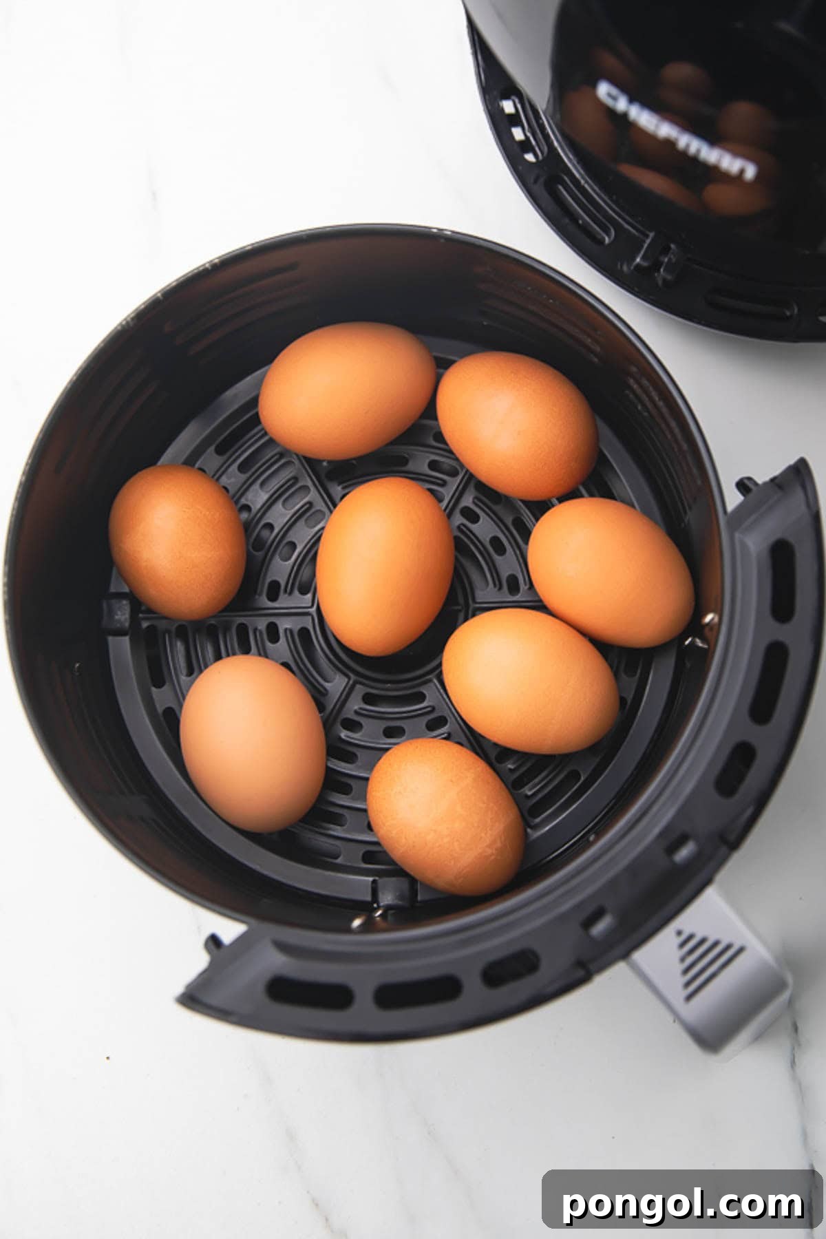 Uncooked eggs, in their shell, resting in a round black air fryer basket.