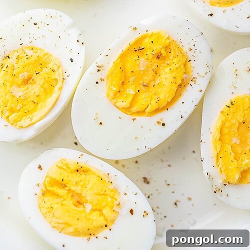 Air fryer hard-boiled eggs, cut in half and seasoned with black pepper, resting on a plate.