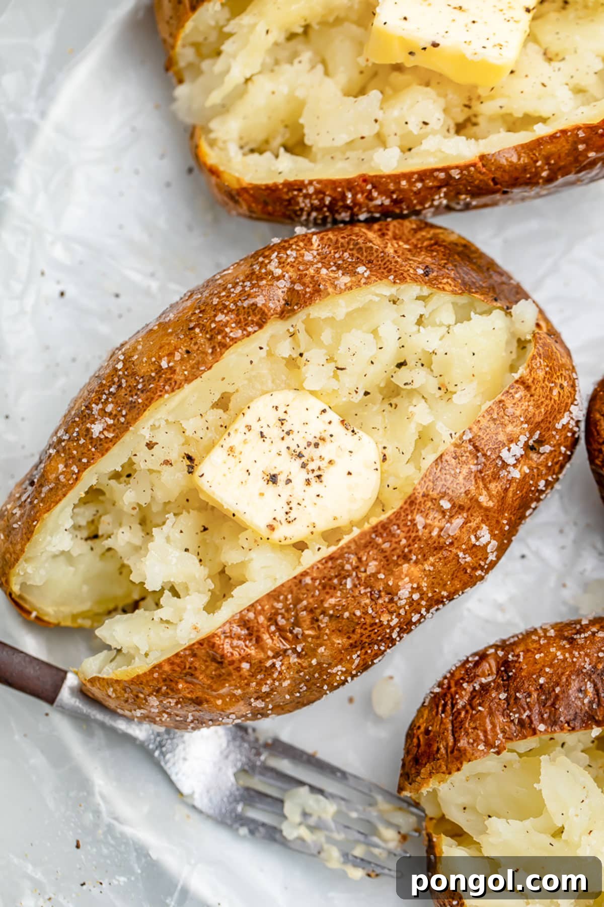 Air fryer baked potato crusted in salt, split in the middle and fluffed, then topped with butter and pepper.