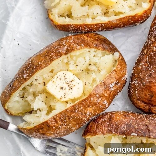 Air fryer baked potato crusted in salt, split in the middle and fluffed, then topped with butter and pepper.
