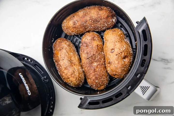 Air fryer baked potatoes in a small round black air fryer basket.