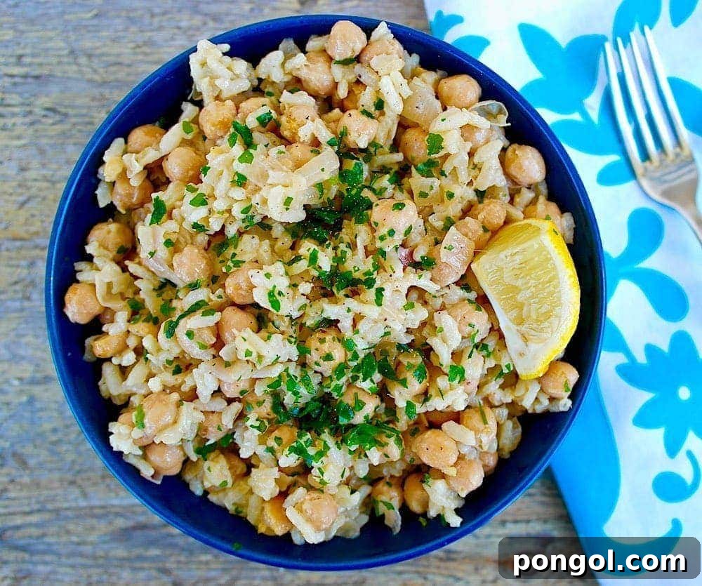 A rustic bowl of Greek chickpeas and rice, garnished with fresh herbs and a drizzle of lemon-tahini dressing, offering a wholesome Mediterranean meal.
