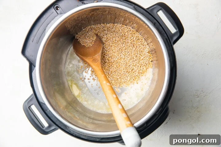 Steel cut oats being sautéed in melted butter inside an Instant Pot with a large wooden spoon.