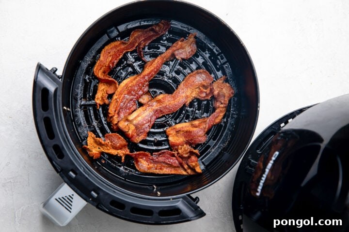 Crispy Air Fryer Bacon 7 Fully cooked strips of bacon in a round air fryer basket, golden and crispy.