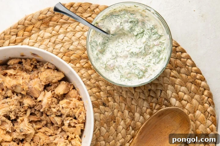 Creamy dill dressing in a small glass bowl next to a bowl of canned salmon.