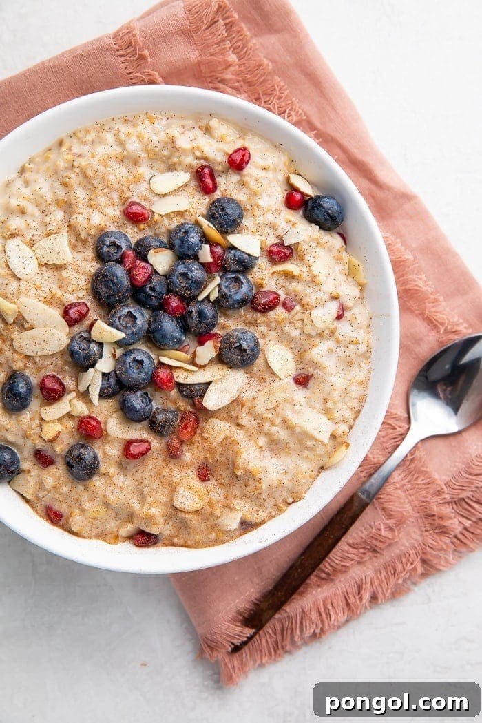 Creamy Overnight Steel Cut Oats 4 A charming bowl of overnight steel cut oats adorned with colorful fruit, a pink napkin, and a spoon, illustrating a delightful and wholesome breakfast scene.