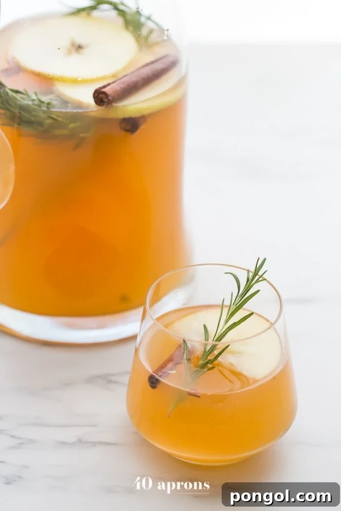 A refreshing red big batch cocktail served in a stylish large dispenser with sliced fruit and garnishes, ideal for easy self-service at a party.